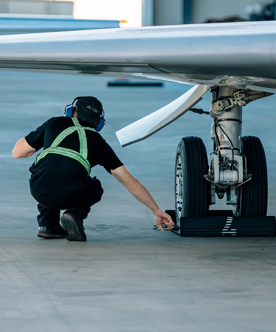 Aircraft management team member placing wheel bloke on private jet